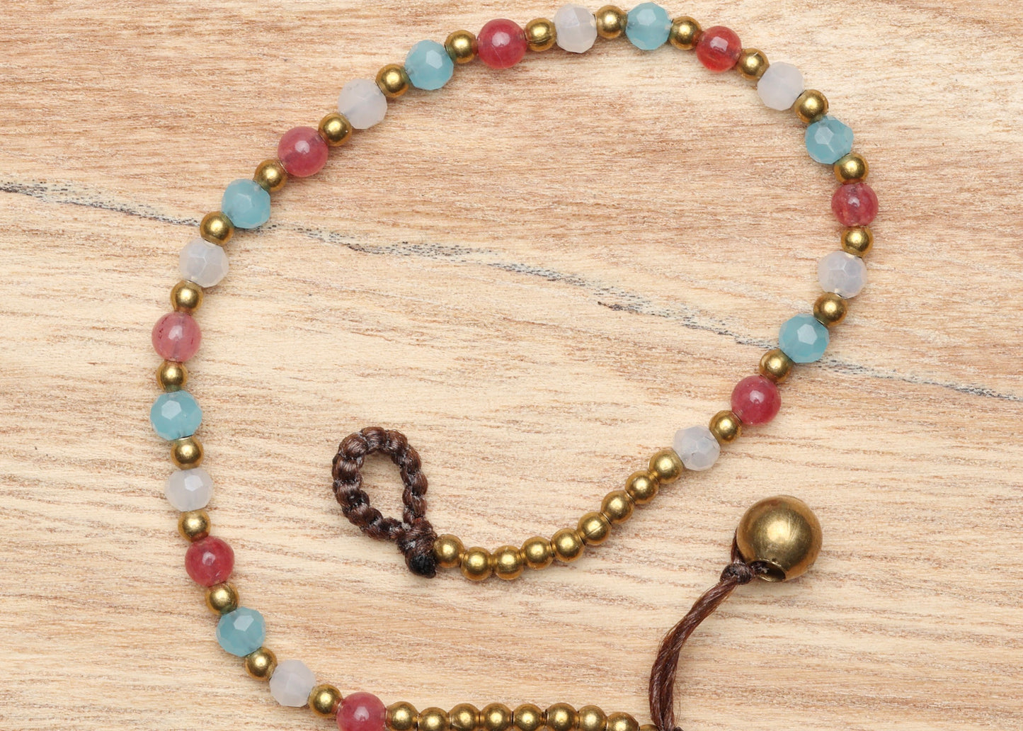 A crystal healing bracelet made of faceted Amazonite crystals on a cotton cord with brass beads