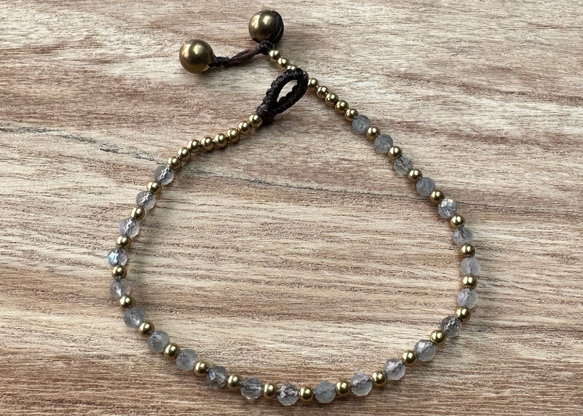 A crystal healing bracelet made of faceted Labradorite crystals on a cotton cord with brass beads