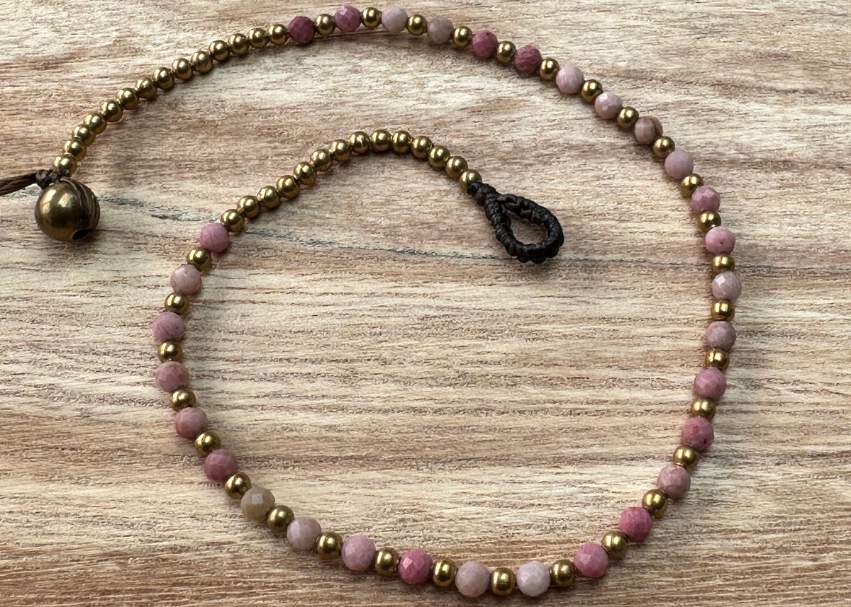 A crystal healing anklet made of faceted Pink Tourmaline crystals on a cotton cord with brass beads
